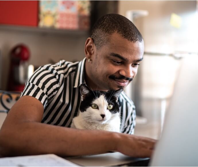 Man som använder bärbar dator och håller en katt