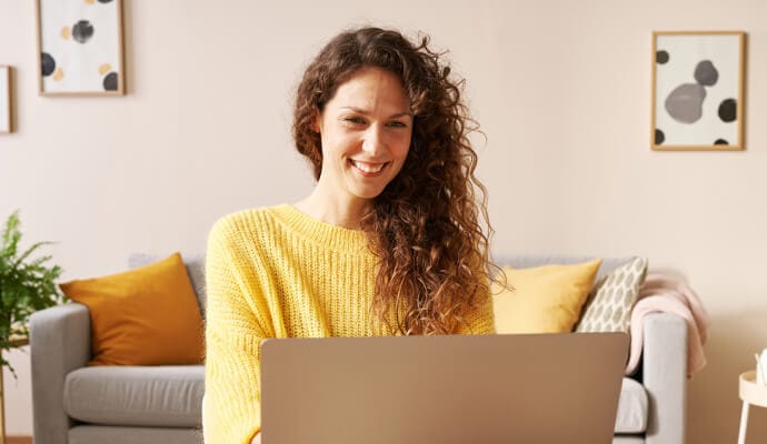 En leende kvinna använder en bärbar dator där Norton Safe Search startas.