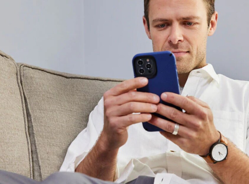 Man i en soffa som tittar på en telefon