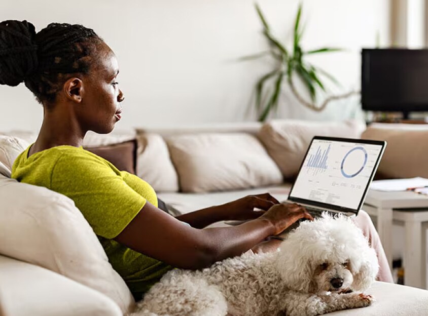 Sittande kvinna med hund som arbetar på en laptop