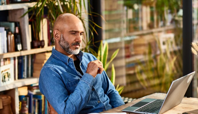 Man som sitter vid ett skrivbord och tittar på en laptop